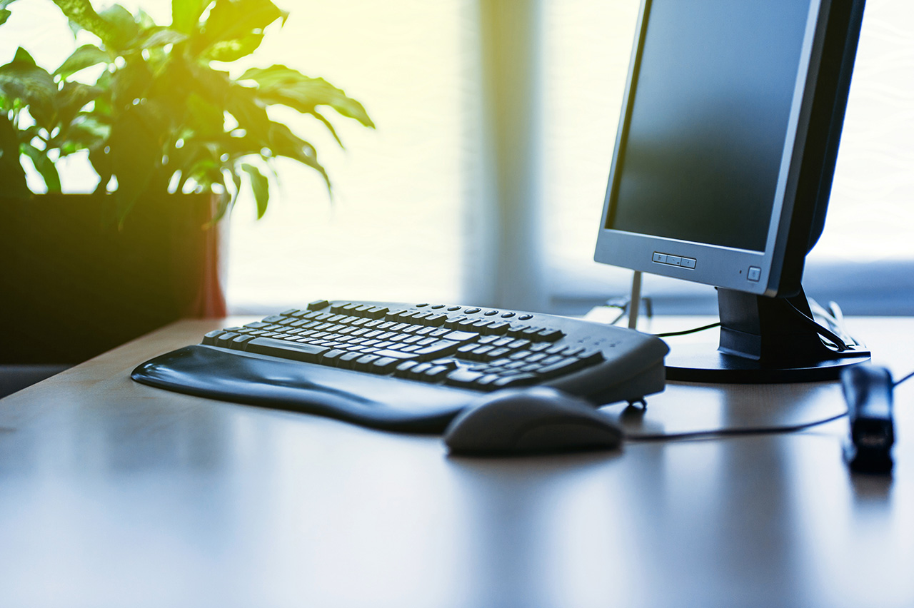 Modern Computer on desk in office lit by sun